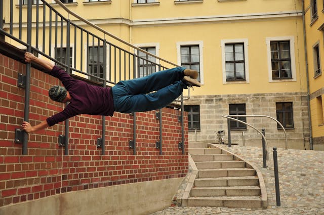 An agile person performs parkour against a city wall