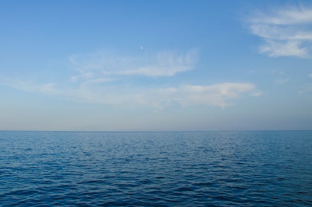 A view across an empty ocean and sky, with clouds overhead.